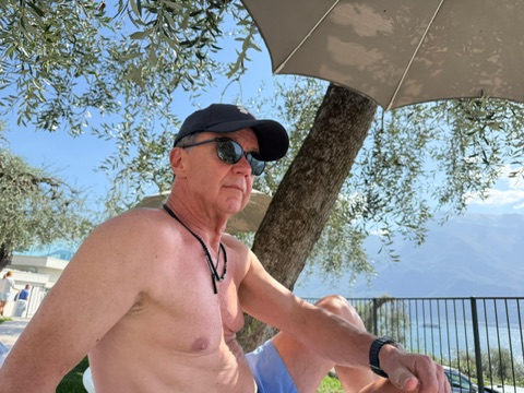 Andi am Pool unter dem Sonnenschirm, im Hintergrund der Gardasee