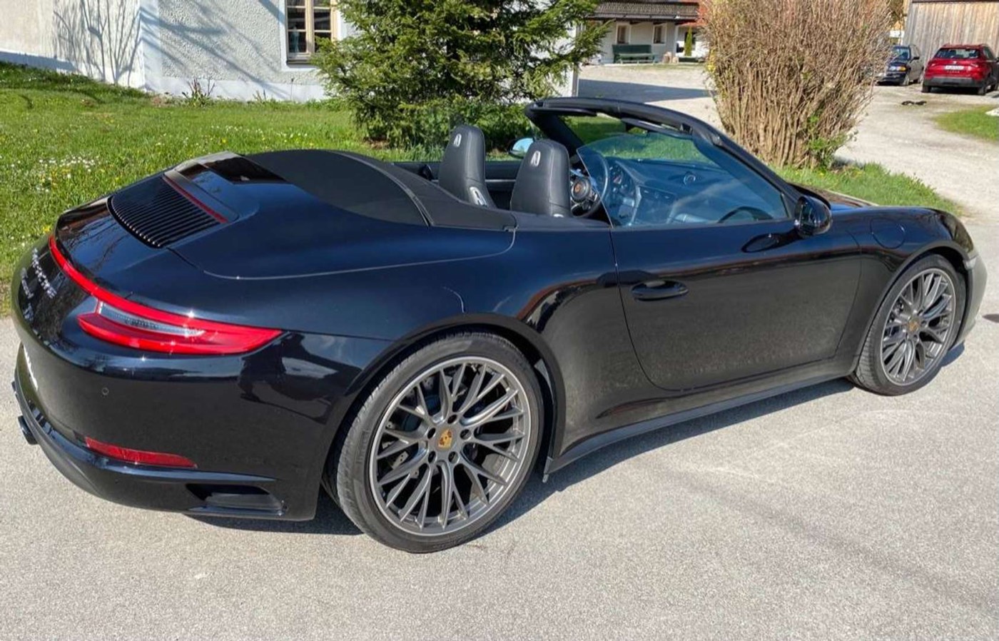 Porsche 911 Carrera 4 Cabrio von hinten mit geöffnetem Verdeck im Sonnenschein